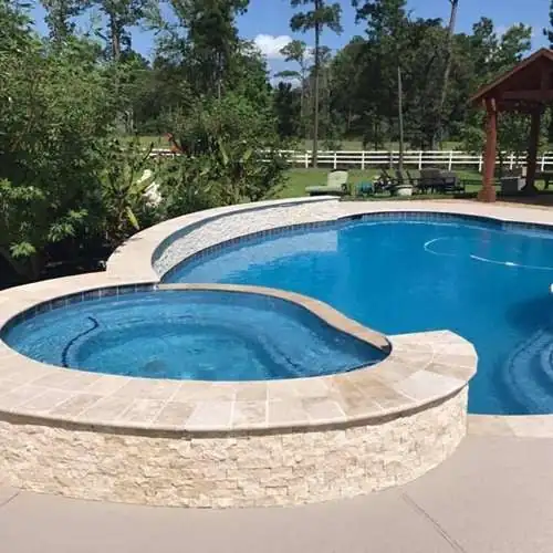 Spa and pool framed by a travertine deck