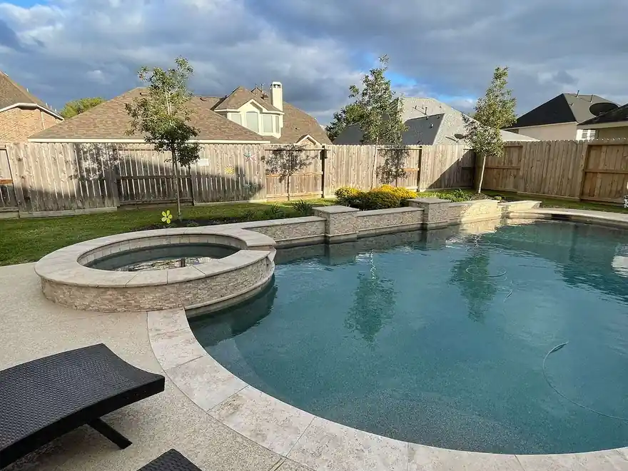 Pool and raised stacked-stone spa at dusk behind a cedar fence