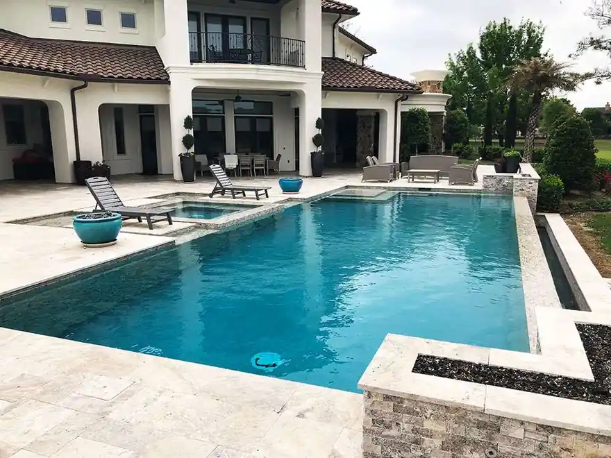 Renovated estate pool with a terracotta-roofed house behind it