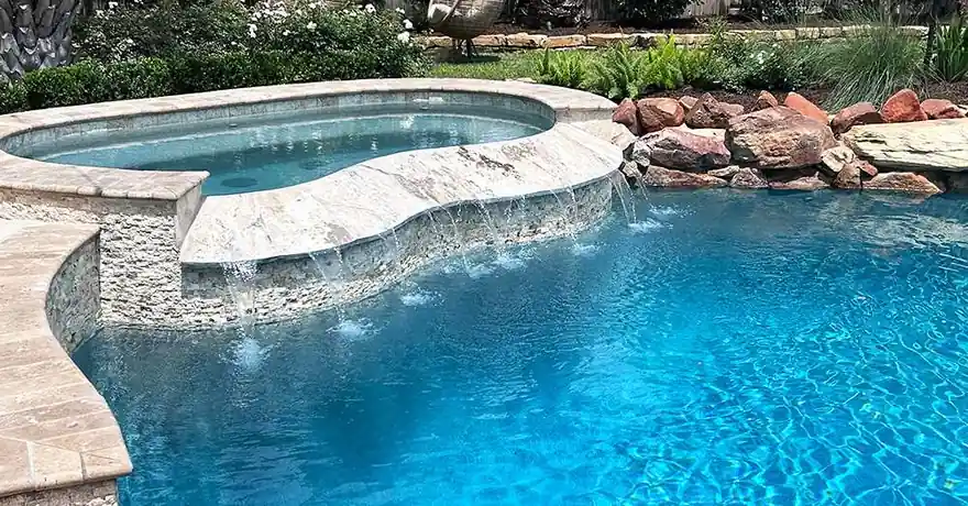 Spa spilling over a boulder edge into the pool